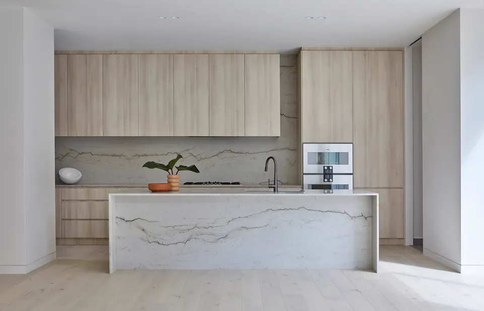Light wood kitchen with stone island, integrated cabinetry, and quiet finish details