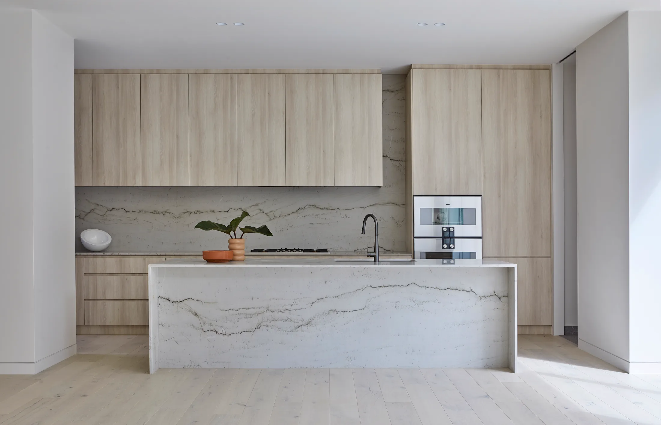 Bright kitchen remodel with island, wood cabinetry, stone surface, and open living area